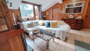 A cozy living room with a sofa, a glass coffee table, and wooden walls. - La Mansardina (Roma)