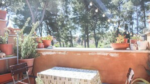 A terrace with terracotta pots, a table with a patterned tablecloth, and string lights. - La Mansardina (Roma)