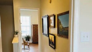 A hallway with wooden flooring, a white door, and a wall with framed pictures. - Sunrise Deck and Boat Slip. Peace and Fun!  (Johnson City)