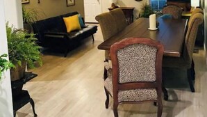 A living room with a dark-colored sofa, a wooden dining table with chairs, a television, and decorative wall art. - Sunrise Deck and Boat Slip. Peace and Fun!  (Johnson City)