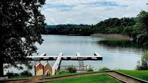 A grassy area with a wooden dock extending into a lake, surrounded by trees and a clear sky. - Sunrise Deck and Boat Slip. Peace and Fun!  (Johnson City)