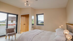 A bedroom with a bed, a chair, a window, and a door. - The Cabin (Dunvegan)