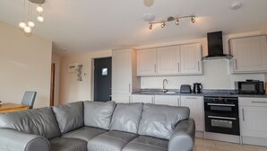 A modern kitchen with white cabinets, a black oven, and a microwave. - The Cabin (Dunvegan)
