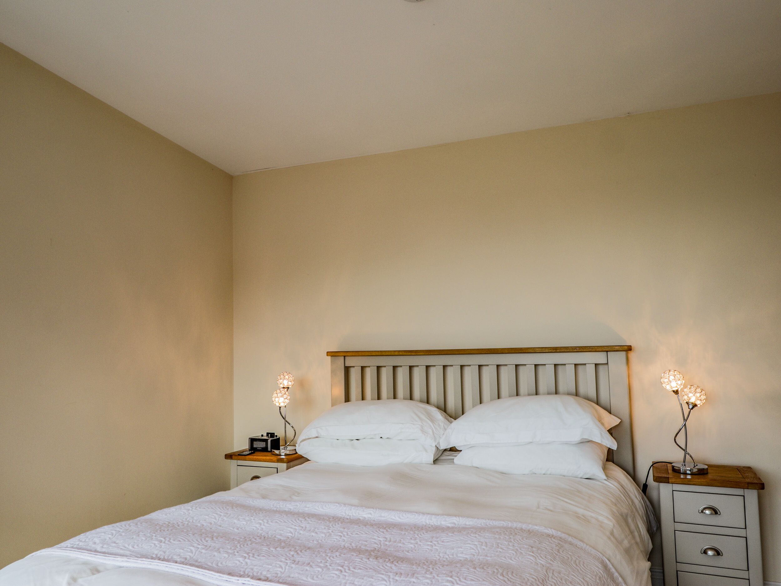 A bedroom with a bed, two bedside tables, and a nightstand.