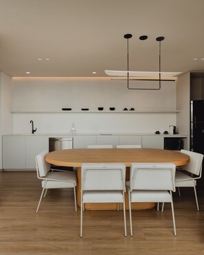 A modern kitchen with a central island, white cabinetry, and a dining area with a round table and white chairs. - Feeling Residences (Medellín)