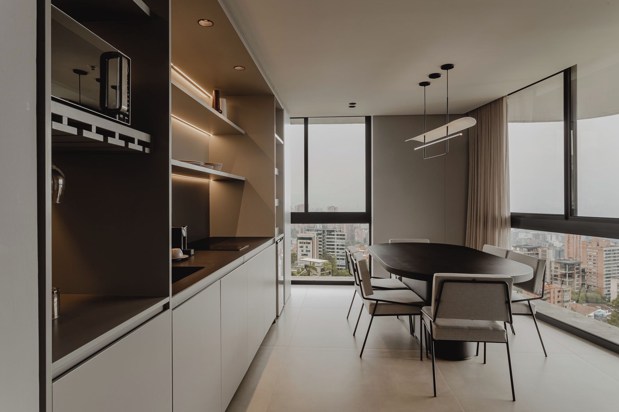Une cuisine moderne avec un coin repas, de grandes fenêtres et une vue sur la ville.