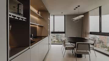 A modern kitchen with a dining area, large windows, and a view of the city.