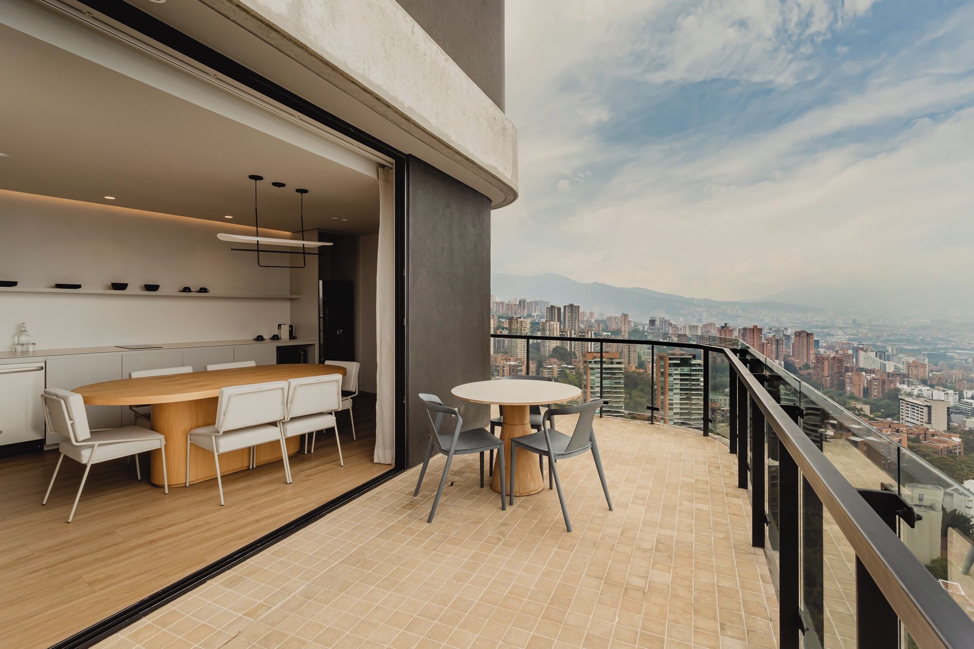 Un balcone moderno con zona pranzo, angolo cottura e vista sulla città.