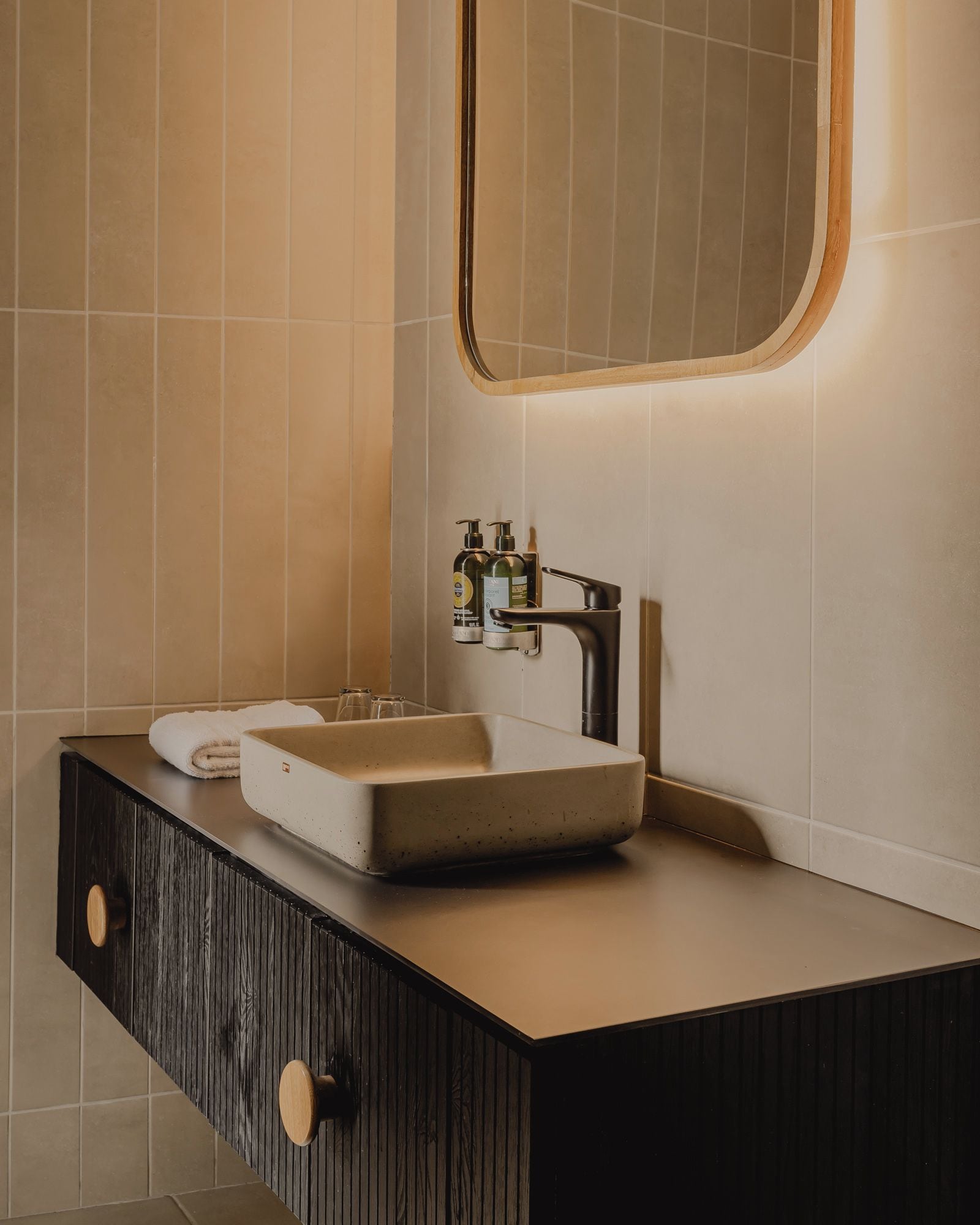 A bathroom with a rectangular sink, a mirror with a wooden frame, and a dark wooden cabinet with a drawer.
