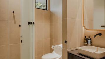 Un baño moderno con inodoro, lavabo y zona de ducha.