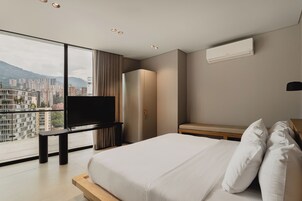 Una habitación de hotel moderna con una cama grande, una televisión de pantalla plana, un armario y vistas a la ciudad.