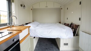 Une pièce compacte et bien éclairée, comprenant un lit, une petite kitchenette et une fenêtre laissant entrer la lumière naturelle.