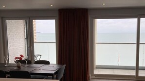 A balcony with a view of the sea, a dining table with chairs, and a large window with curtains. - 24 Breakwaters - Sandown Bay - Isle of Wight (Sandown)