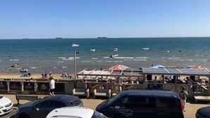 A beachside view with a wooden pier, umbrellas, and a clear blue sky. - 24 Breakwaters - Sandown Bay - Isle of Wight (Sandown)