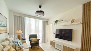 En moderne stue med sofa, stol, fjernsyn og loftventilator.