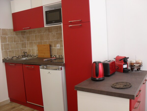 A compact kitchen with red cabinetry, a microwave, a coffee maker, and a toaster. - Beautiful, Spacious, 1 Bedroom Apt in Cannes (Cannes)