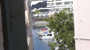 Ein Yachthafen mit vertäuten Booten, Gebäuden im Hintergrund und einem Baum im Vordergrund.