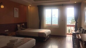A hotel room with two beds, a balcony with a view, and a desk with a chair. - Lien Minh Hostel & Homestay-  Family Balcony Room With Mountain View (Sa Pa)