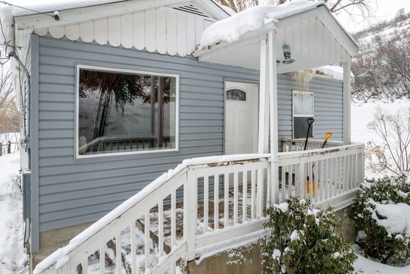 A single-story house with a covered porch, a front door, and a large window.