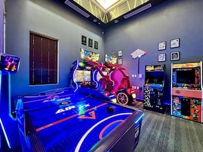 Ein Raum mit Billardtisch, Spielautomaten und einem neonbeleuchteten Auto.