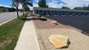 A motel with a parking lot, a sidewalk, and a row of trees. -  CB&M Duchesne Hotel (Duchesne)