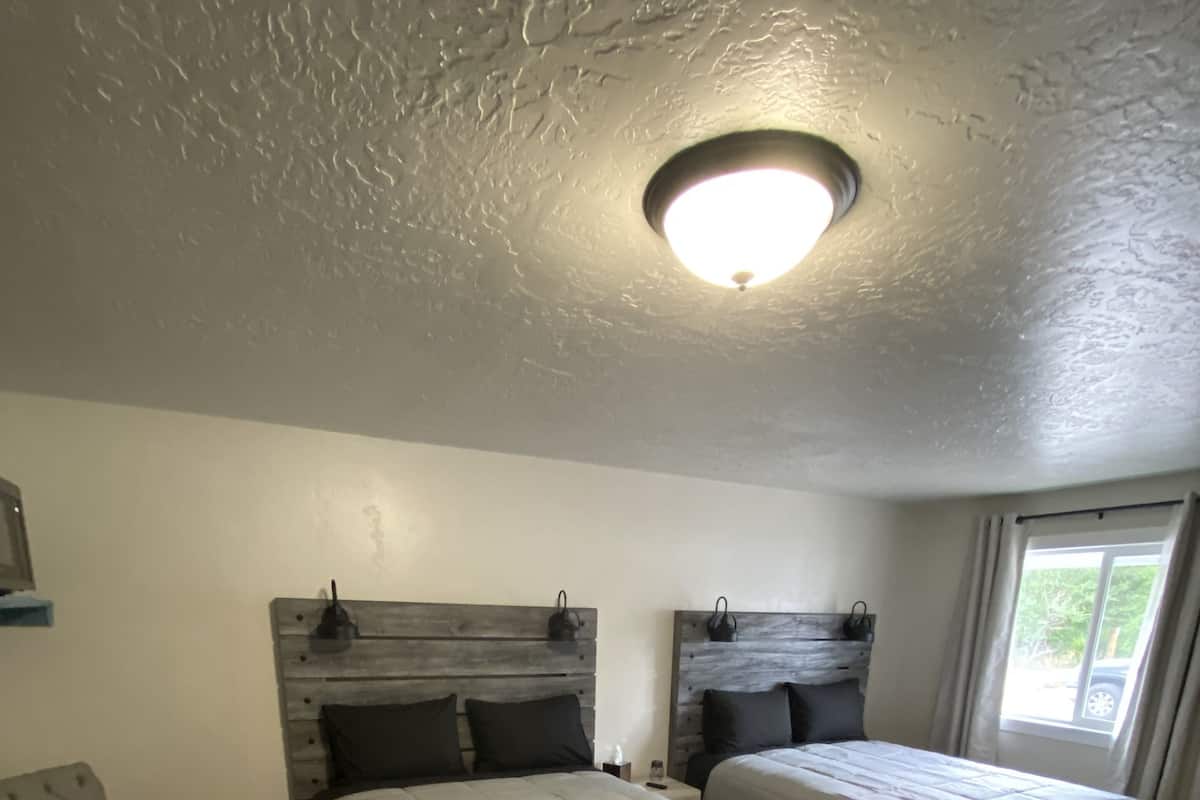 A bedroom with two beds, a chair, and a ceiling light.