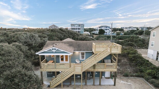 A beachfront house with a wooden deck and a staircase leading to a balcony. - Outer Banks Haven: Pet-Friendly, Walk-to-Beach, EV Charging, Updated Kitchen (Kitty Hawk)