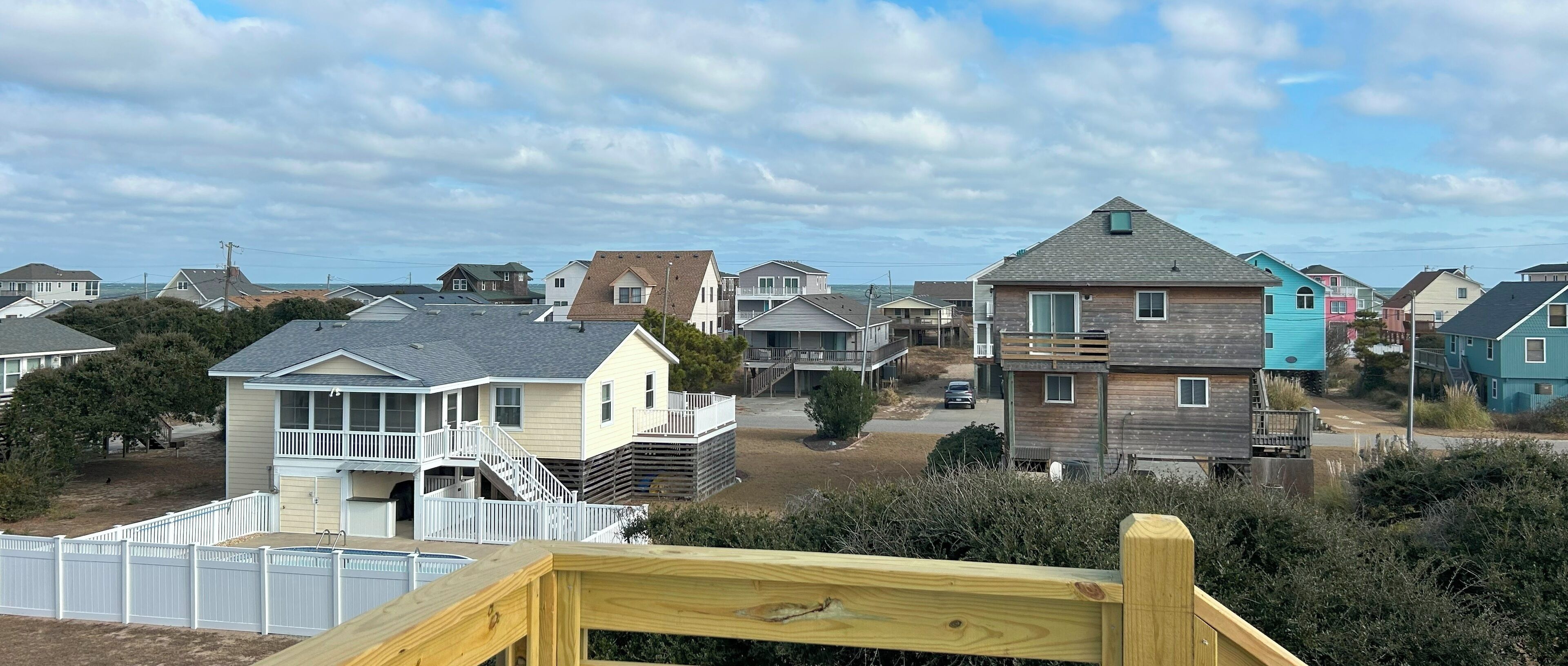 Un quartier résidentiel où l’on trouve des maisons de différents styles architecturaux, dont une maison remarquable dotée d’un balcon et d’une terrasse en bois.