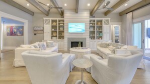 Een ruime woonkamer met witte banken, een open haard en een flatscreen televisie erboven.