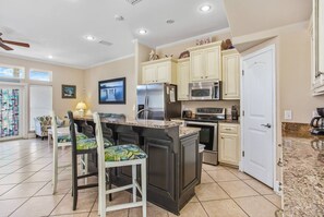 Una cocina moderna con una isla central, electrodomésticos de acero inoxidable y muebles de color claro.