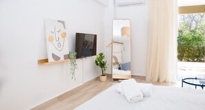 A modern bedroom with a bed, a mirror, a potted plant, and artwork on the wall. - Boho Blu Apartment by A&D Properties (Markopoulo Mesogaias)