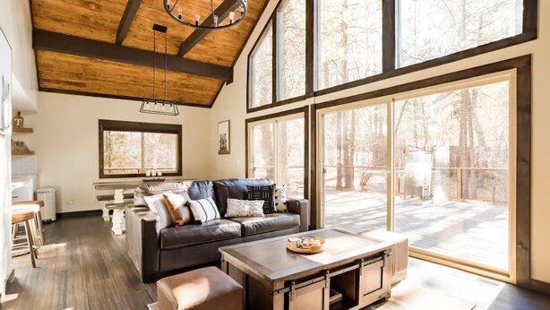 A spacious living room with a large window, a wooden ceiling, and a leather sofa. - Mountain Escape minutes from Village & Ski Slopes (Big Bear Lake)