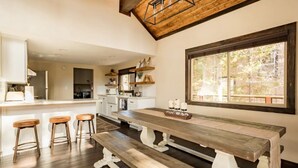 A spacious kitchen with a wooden bench, bar stools, and a large window offering a view of the outdoors. - Mountain Escape minutes from Village & Ski Slopes (Big Bear Lake)
