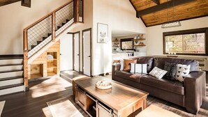 A spacious living area with a wooden staircase, a leather sofa, and a dining table. - Mountain Escape minutes from Village & Ski Slopes (Big Bear Lake)