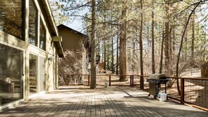 A wooden deck with a barbecue grill, surrounded by tall trees. - Mountain Escape minutes from Village & Ski Slopes (Big Bear Lake)