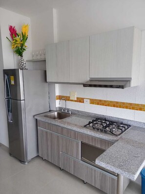 Eine moderne Küche mit einem Edelstahlkühlschrank, einem Gasherd und Holzschränken.
