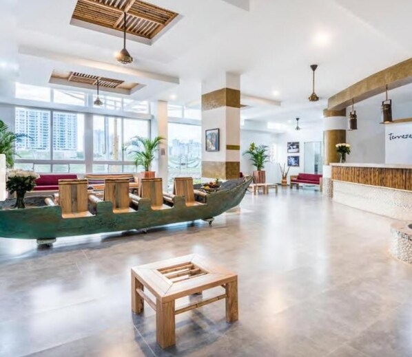 A spacious lobby with a long wooden boat display, a reception desk, and a seating area with a small table.