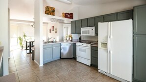 Eine moderne Küche mit grauen Schränken, einem weißen Kühlschrank, einer Mikrowelle und einem Geschirrspüler.