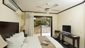 Een hotelkamer met een bed, een televisie, een bureau en een balkon met uitzicht.