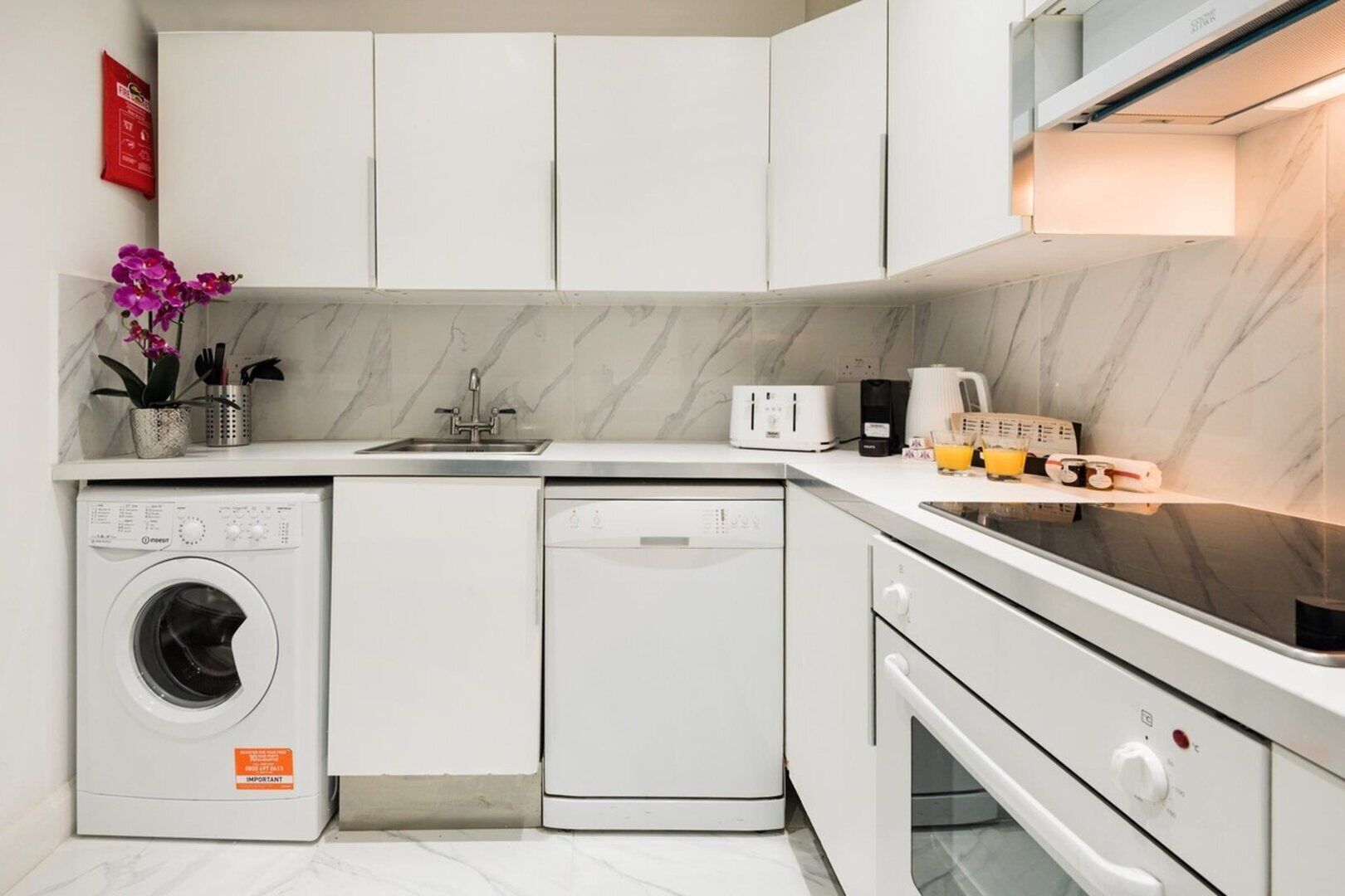 Une cuisine compacte équipée d’un lave-linge, d’un lave-vaisselle et d’un four.