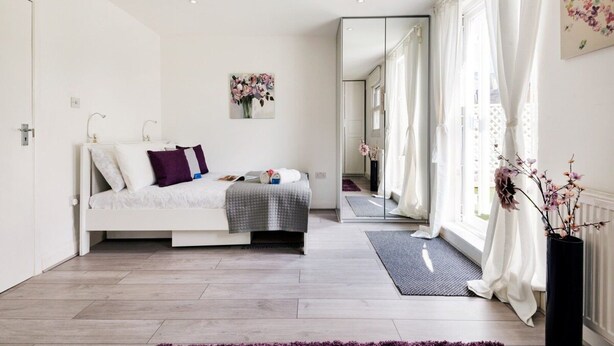 Quarto moderno com cama, espelho e vista para o exterior.
