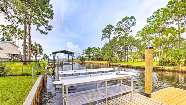 A wooden dock with a metal bench and a covered seating area over a canal. - Waterfront Home: Spectacular On-Site Fishing! (Panacea)
