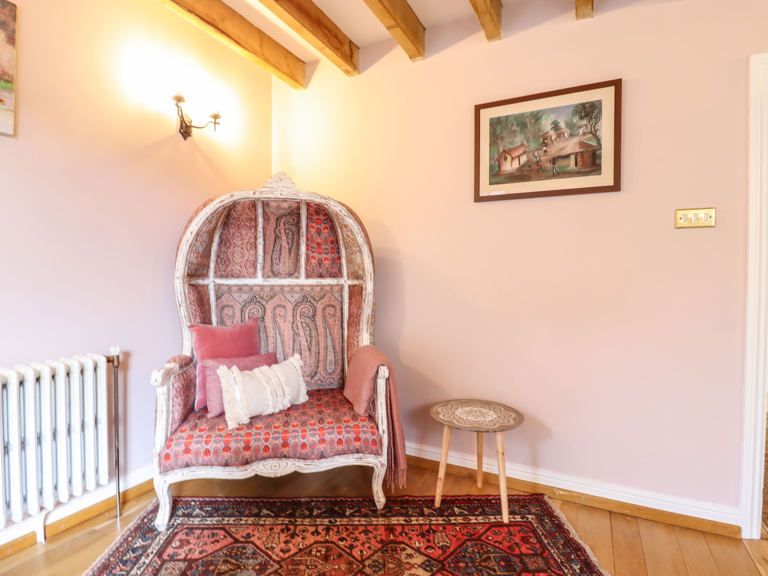 Ein gemütliches Zimmer mit einem gemusterten Sessel, einem kleinen runden Tisch und einem Bild an der Wand.