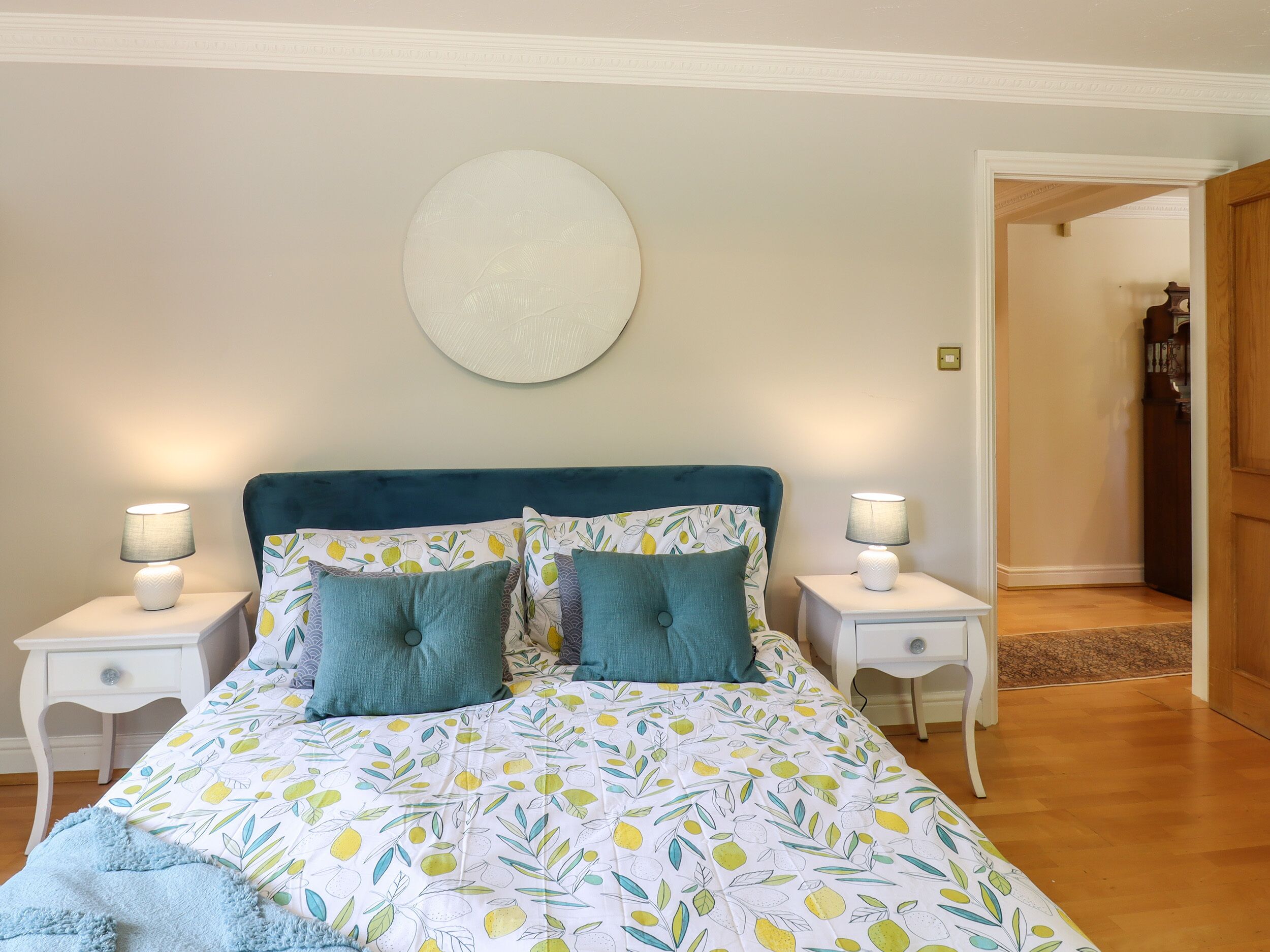 A bedroom with a bed, two bedside tables, and a round wall decoration.