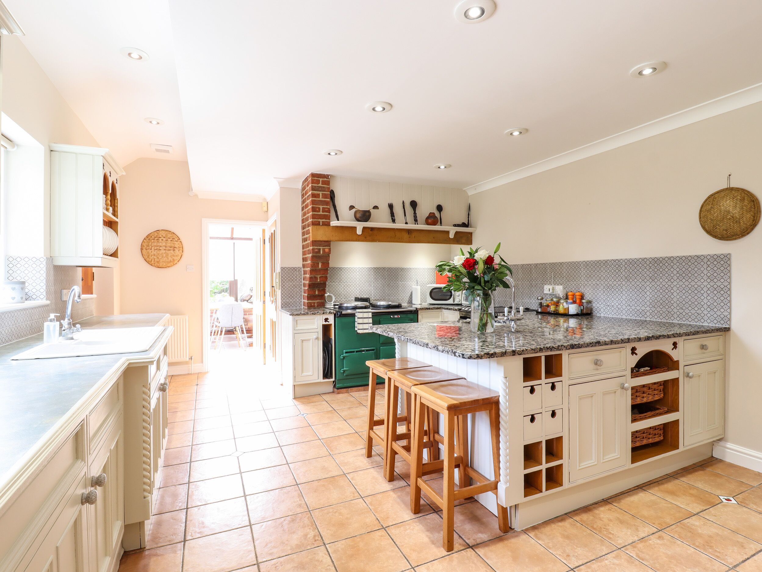 A spacious kitchen with a central island, green cabinets, and a view to the dining area.