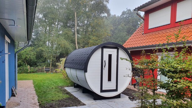 Una estructura cilíndrica amb una porta, situada en un camí pavimentat en una zona de jardí.