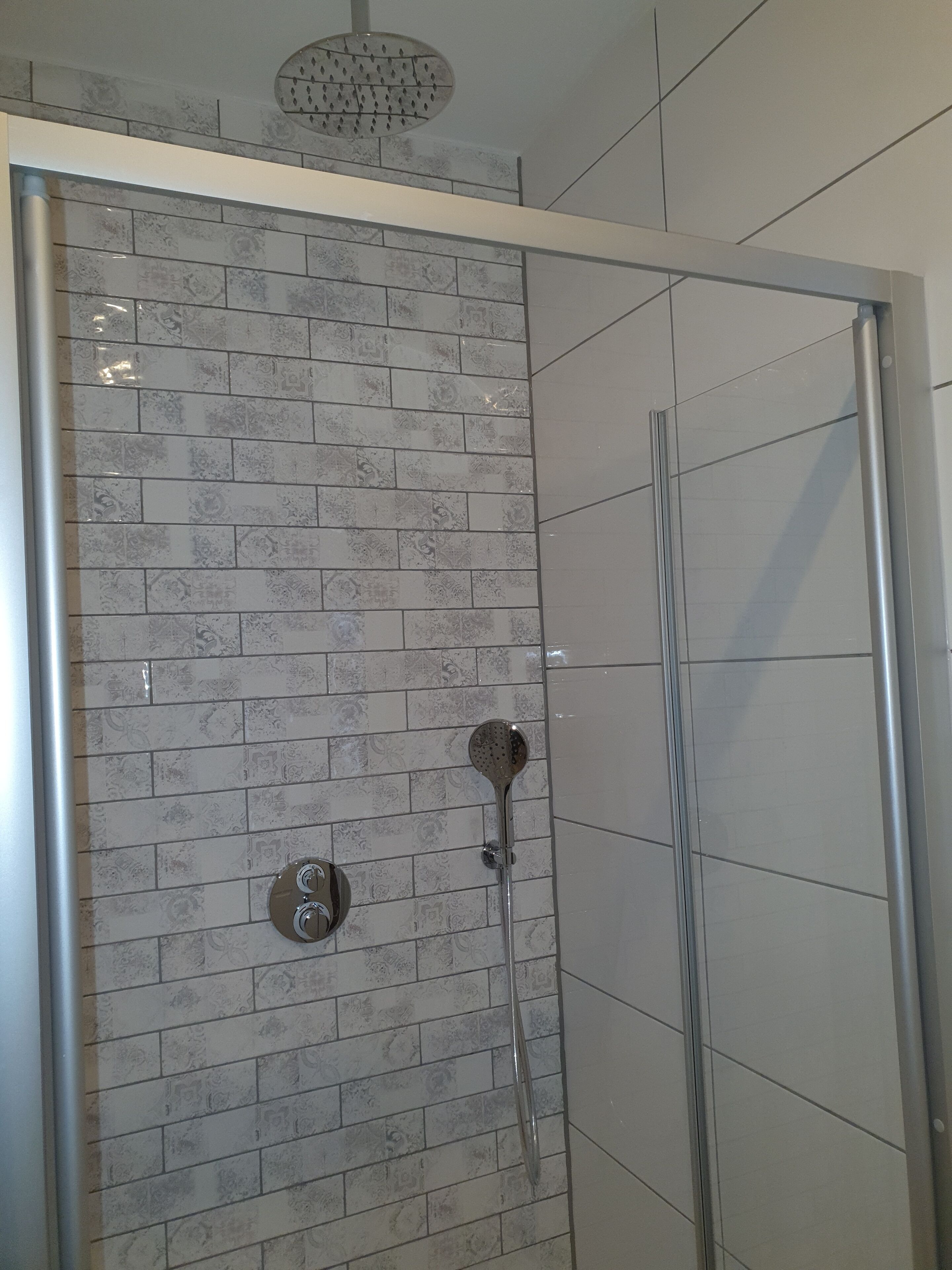 Doccia con porta in vetro, soffione e manopola di regolazione.