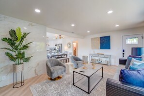 Uma sala de estar moderna com um sofá, poltronas, uma mesa de centro e uma planta em vaso.