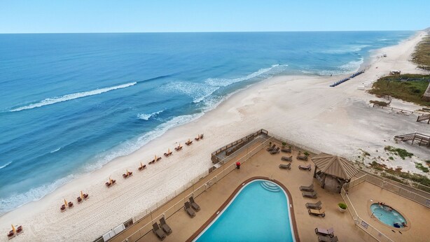 A beach resort with a swimming pool, sun loungers, and a view of the ocean. - Treasure Island 0809 (Panama City Beach)