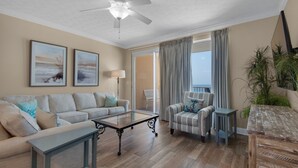 A living room with a sofa, armchair, coffee table, and a ceiling fan. - Treasure Island 0809 (Panama City Beach)